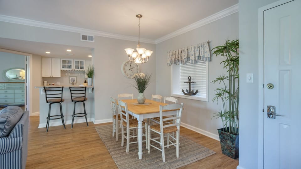 A classic chandelier anchors the room, while the dining table comfortably seats six—perfect for shared meals or game nights.