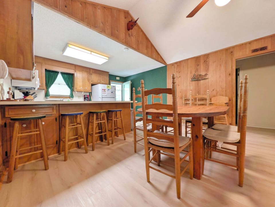 This cozy dining area features handcrafted wooden furniture, a breakfast bar with stools, and warm wood-paneled walls—your perfect spot for family meals and morning coffee.