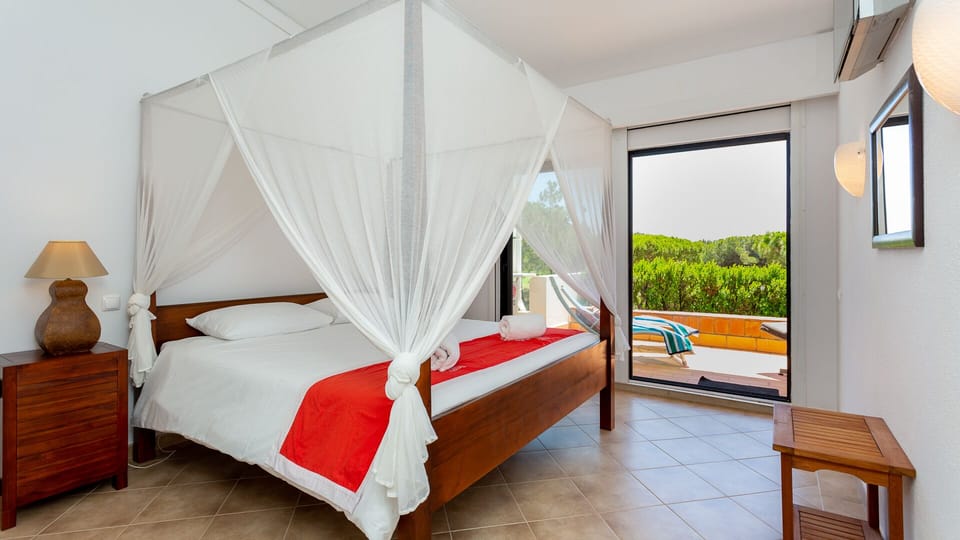 King bedroom with view to its sun terrace and pine canopies beyond