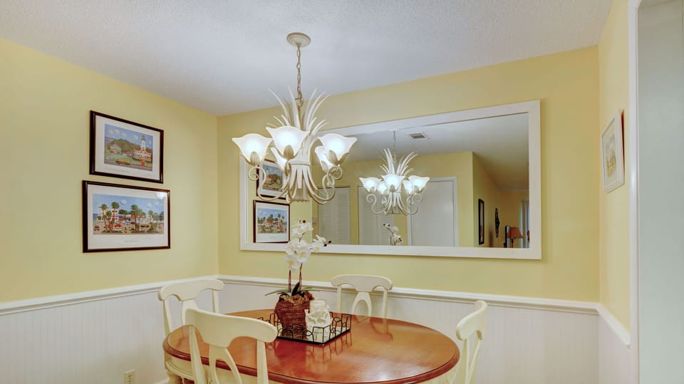 Dining Table for 4 – Ocean Walk W-14, St. Simons Island - Golden-hour dinners, card games, and second servings happen here. This round table seats four and sits under soft lighting, surrounded by coastal art and calm.