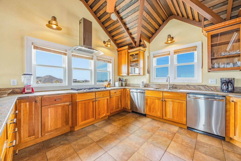 Your gourmet kitchen features warm wood cabinetry, stainless appliances, and a stunning vaulted wood-beam ceiling. Expansive windows frame the mountain and water views while you cook and gather.