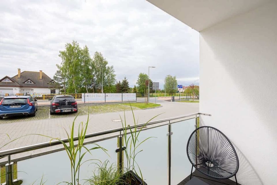 A private outdoor area with glass railings, featuring potted plants and a small table with chairs.