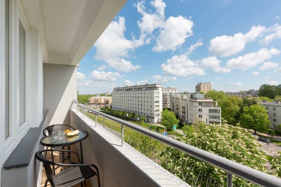 A balcony overlooking a serene urban landscape with greenery and mid-rise buildings.