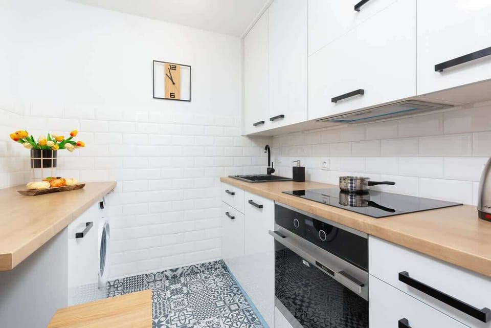 A compact kitchen with white cabinets, wooden countertops, and sleek black appliances.