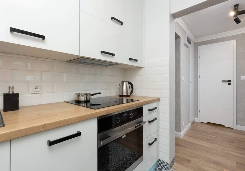 Practical kitchen with white cabinets, wooden countertops and elegant black appliances.