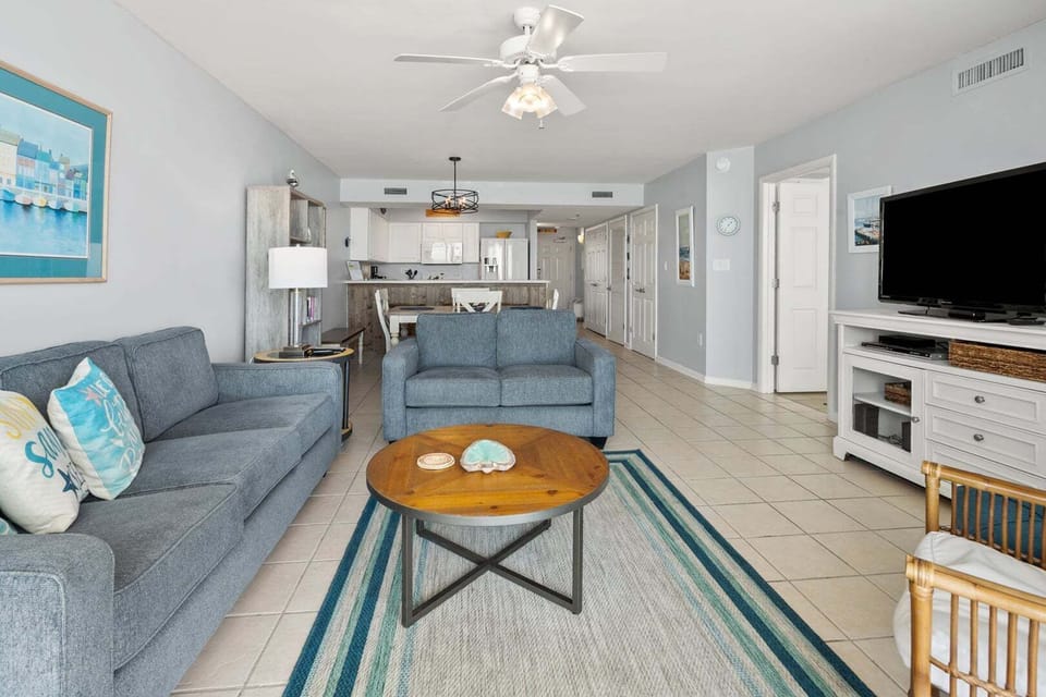 Gray sectional and a blue armchair with the kitchen beyond at Paradise Pointe 4B in Cherry Grove