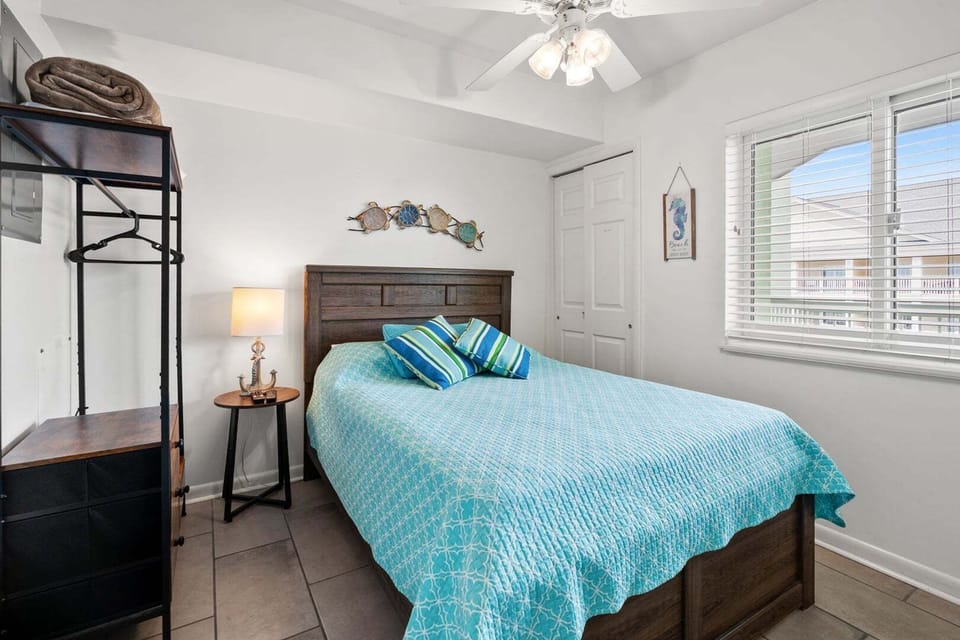 Blue quilt, dark headboard and a shuttered window in a bedroom at Paradise Pointe 4B in Cherry Grove
