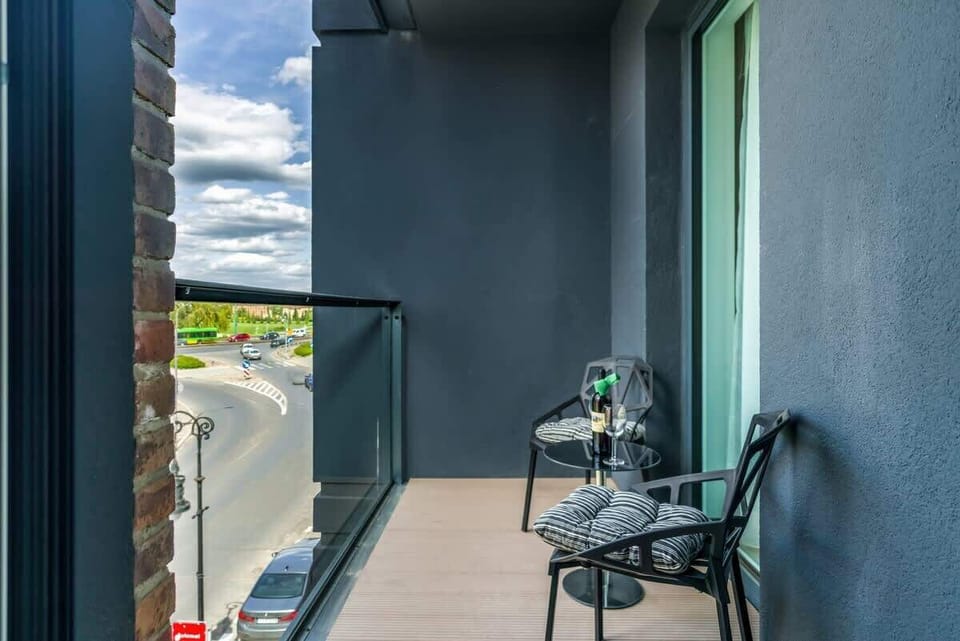 A small balcony with a table and chairs, overlooking a scenic urban area.