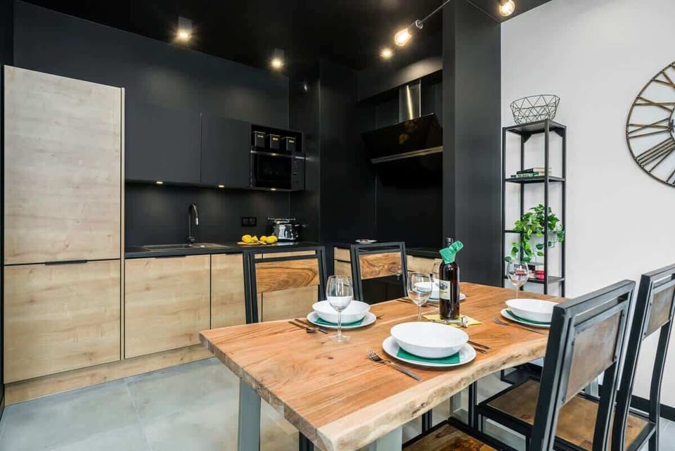 A dining space in the living room, set with stylish dishes and surrounded by green and wood tones.