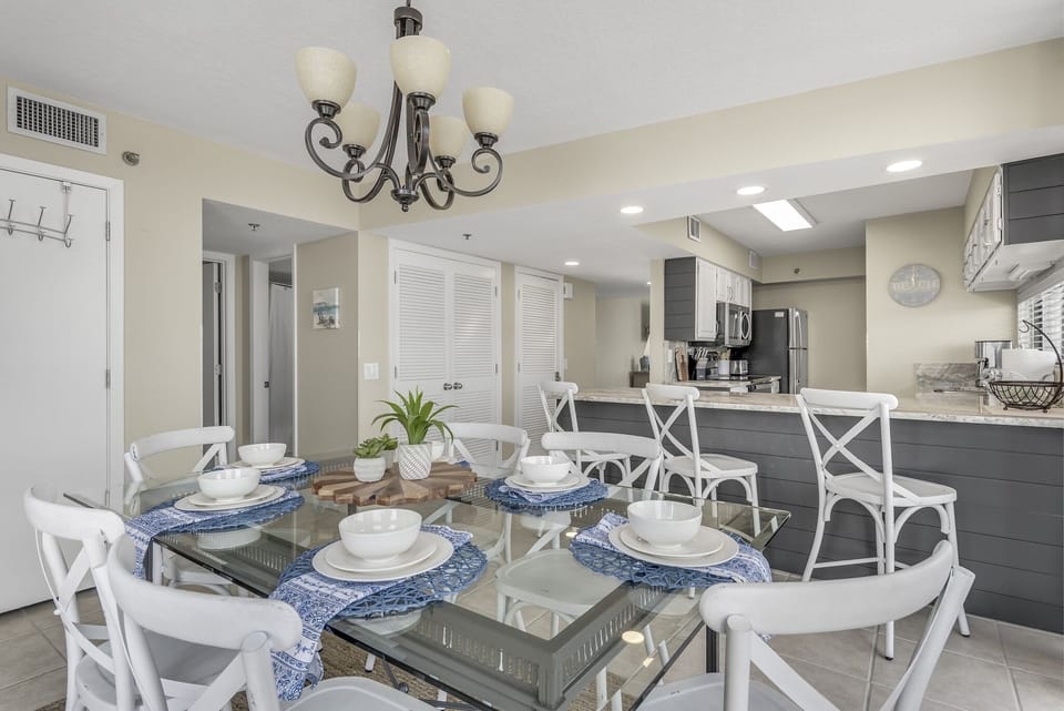 Your elegant dining space features a stunning glass table for eight with beautiful place settings, perfect for memorable meals together.