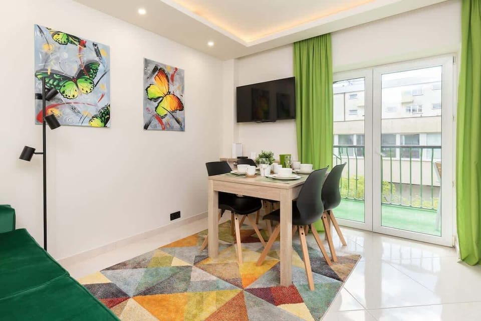 A cozy living room featuring a green sofa with bright yellow cushions, a colorful rug, and decorative wall art.
