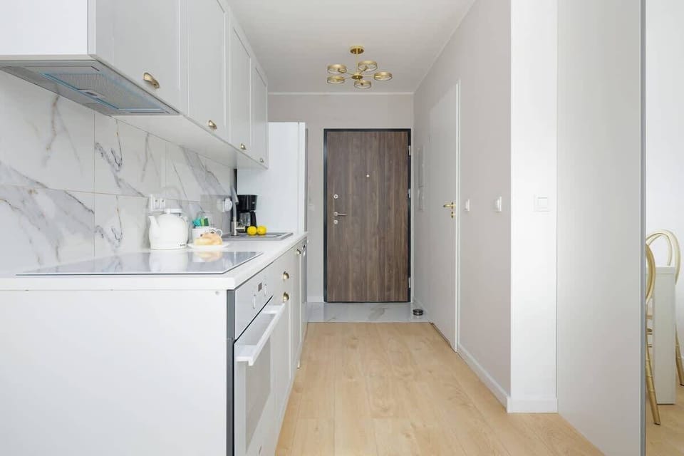 A functional kitchenette with white cabinets with gold handles will lend elegance to the room.