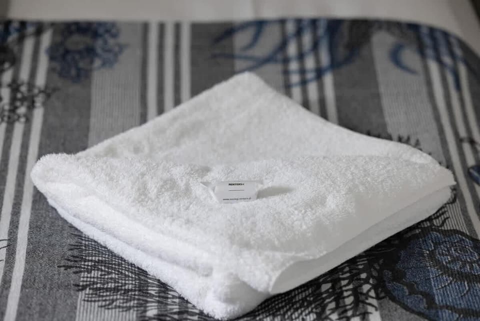 A close-up of a neatly made bed with a folded towel, emphasizing attention to detail and guest comfort in the apartment.