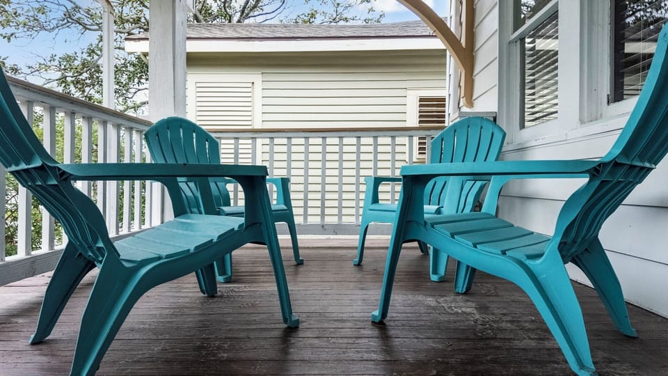 Port Side at M (Upper Left) — a screened porch with teal Adirondack chairs to relax after a beach day.