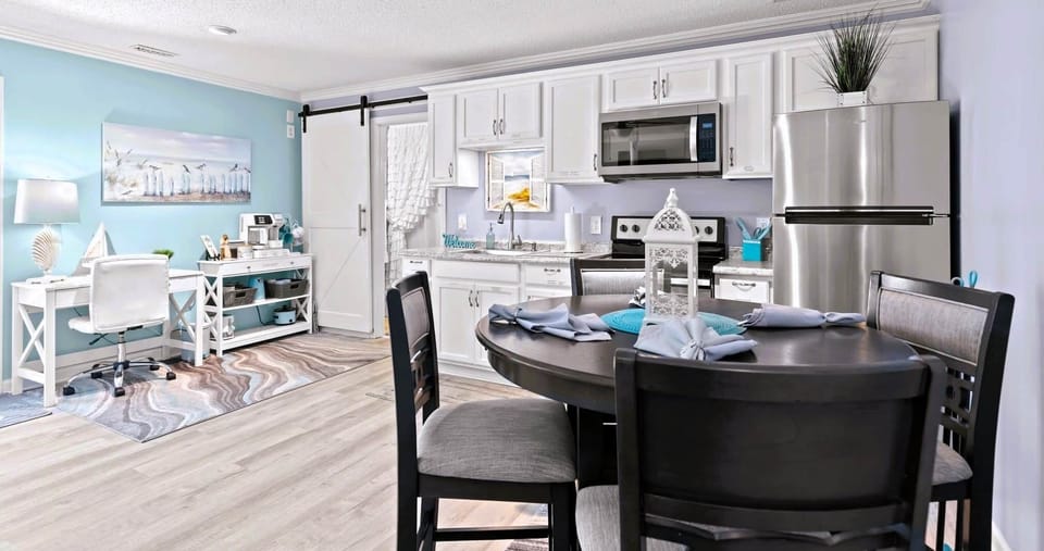 Overall view of open concept which includes dining table, full kitchen, coffee bar and desk .