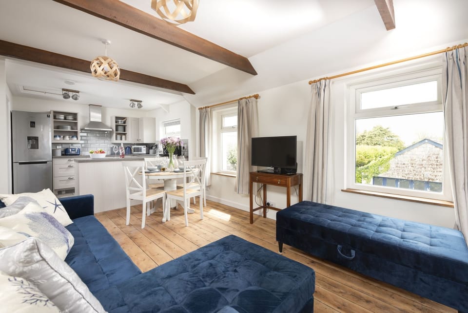 Living room with large foot stool and access to the furnished balcony - Greenfields Coach House