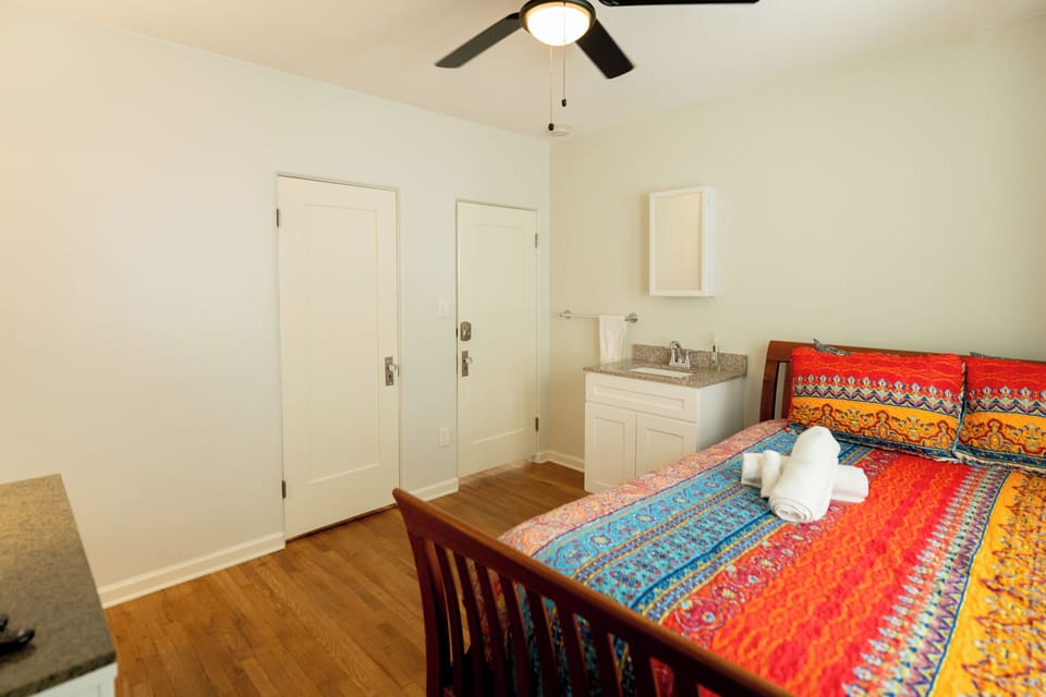 SE Bedroom, with private sink, work station, queen bed, TV and closet