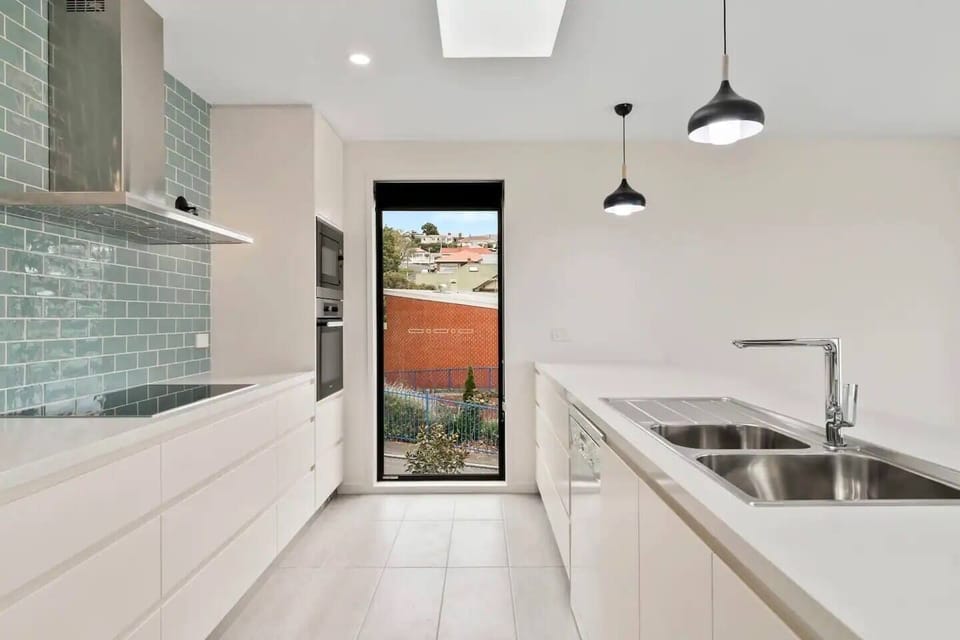 A sleek white kitchen makes it easy to whip up a feast at home and comes fully equipped with modern appliances.
