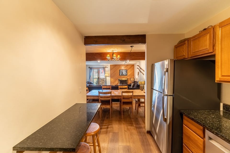 Your fully-equipped kitchen flows seamlessly into the dining area, where rustic beams and warm wood create the perfect atmosphere for memorable meals.
