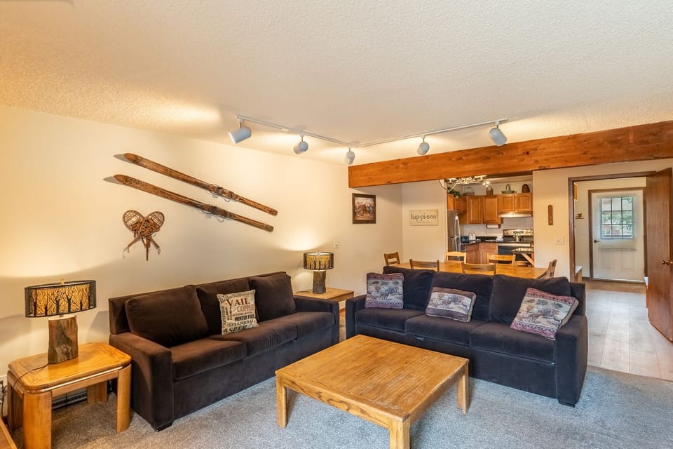 Relax in this cozy mountain-themed living space featuring rustic wood accents, comfortable seating, and an open kitchen perfect for your alpine getaway.