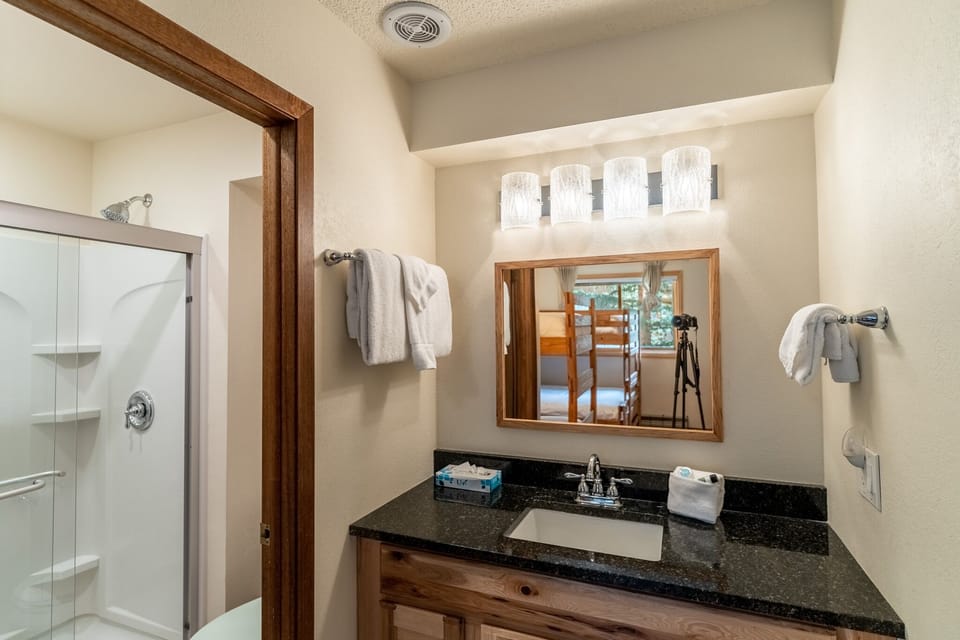 Step into your private bathroom retreat, featuring warm wood accents, granite countertops, and soft towels awaiting your relaxing getaway.