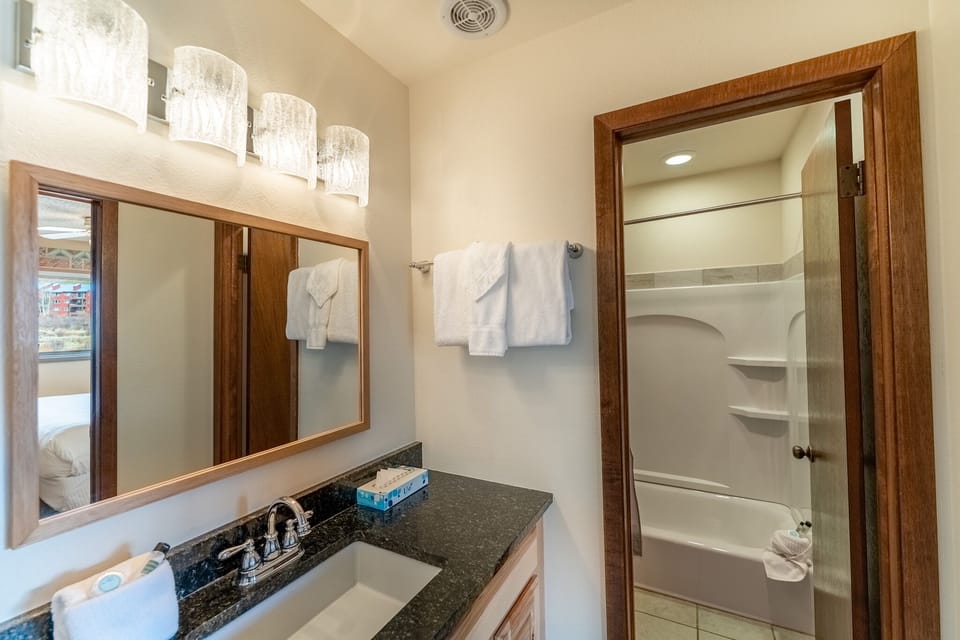 Relax in your bright, modern bathroom with granite countertops, elegant lighting, and fresh towels ready for your comfort.