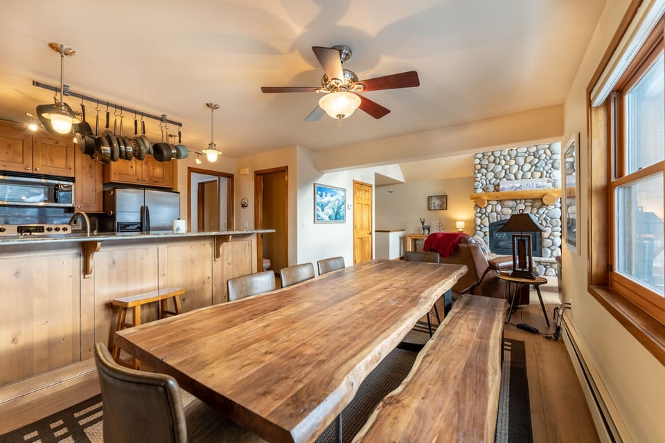 Gather around your rustic dining table where warm wood tones and a crackling fireplace create the perfect atmosphere for memorable meals together.
