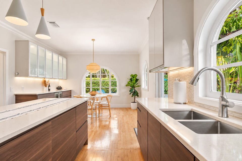 Double sinks and a long stretch of counter make this kitchen easy to cook in, with a straight sightline through to the sunny breakfast nook. Arched windows on both ends keep the whole space feeling open and bright.