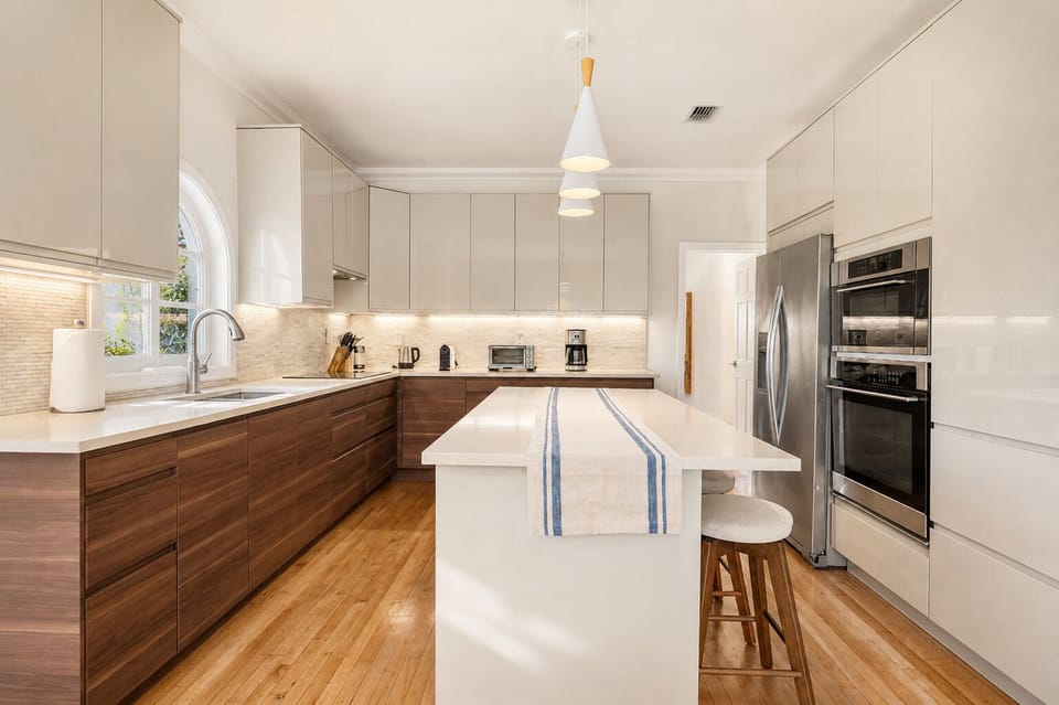 Stainless double ovens, a full-size fridge, and a stocked coffee corner make this kitchen ready for anything, from quick breakfasts to a full holiday spread. Walnut cabinets and a big center island give everyone room to help out or just hang around.