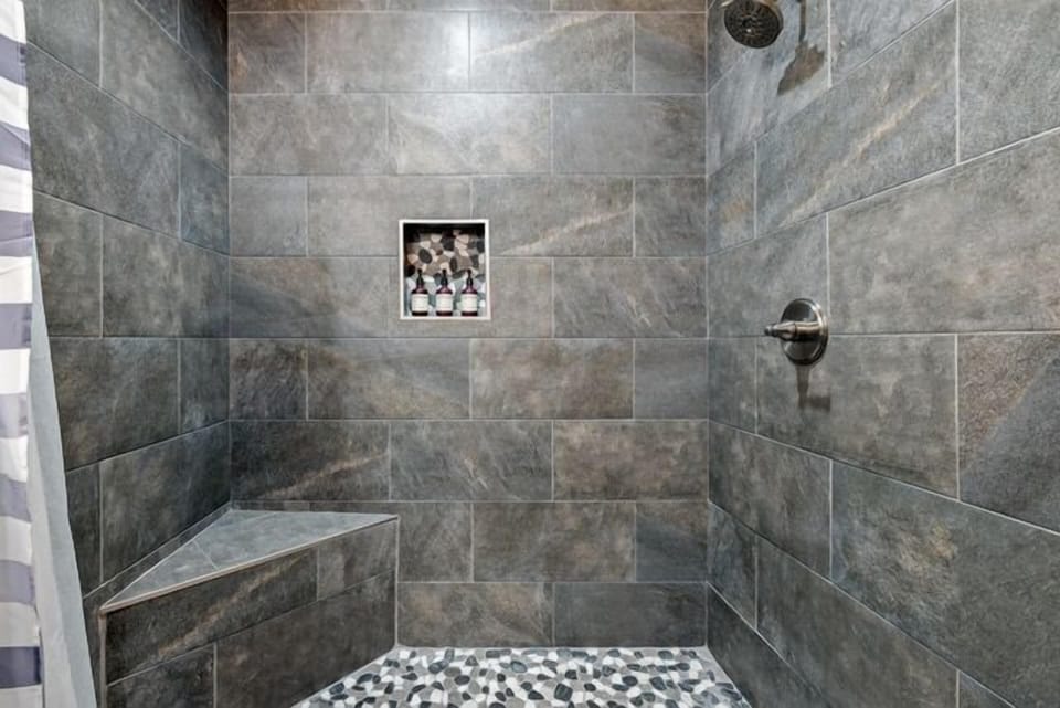 Custom tile and pebble floor walk in shower with bench. 