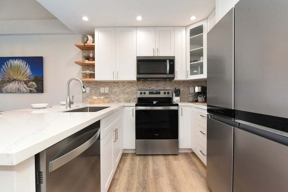 Fully renovated kitchen with quartz countertops, stainless‑steel appliances, and sleek white cabinetry