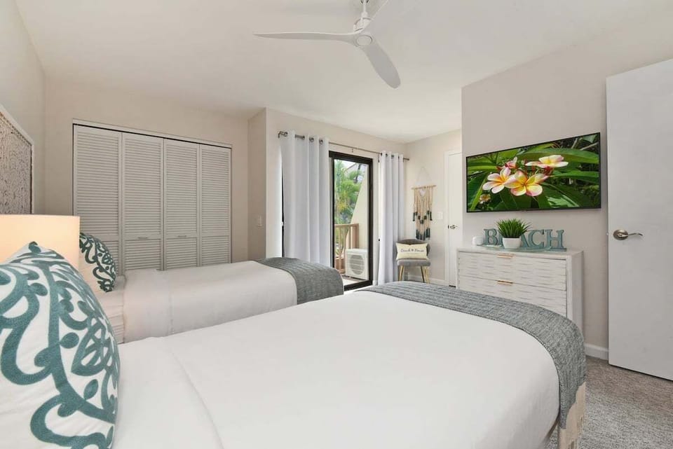 Spacious guest room with twin beds, entertainment center, and direct balcony access