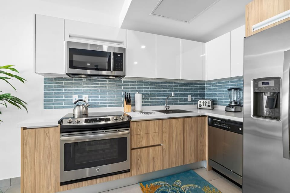Your private bathroom features a sleek glass-enclosed shower, modern vanity with ample storage, and soothing neutral tones that create a spa-like retreat for refreshing after beach adventures.