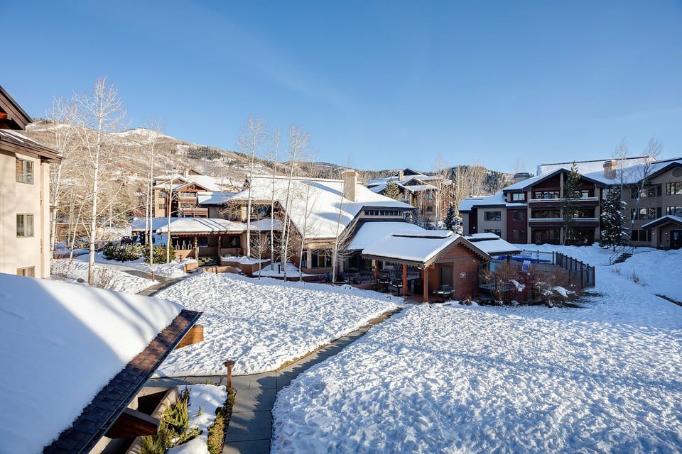 Snow-covered mountain village with ski chalets and pristine winter landscape under bright blue skies.