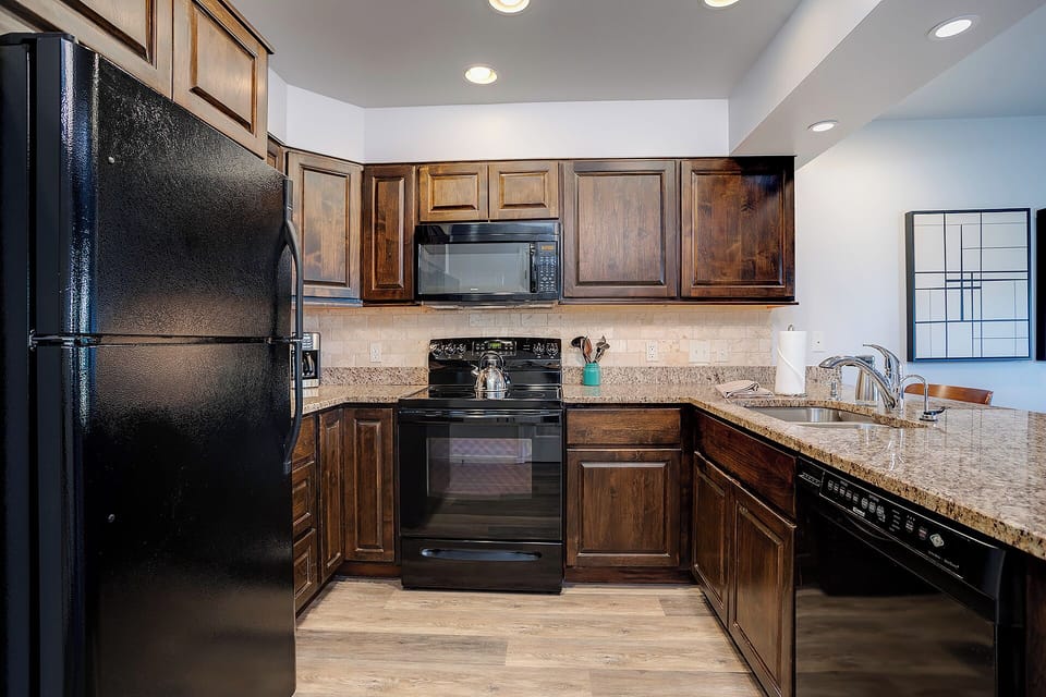 Your fully-equipped kitchen features granite counters, rich wood cabinets, and modern black appliances for memorable home-cooked meals.