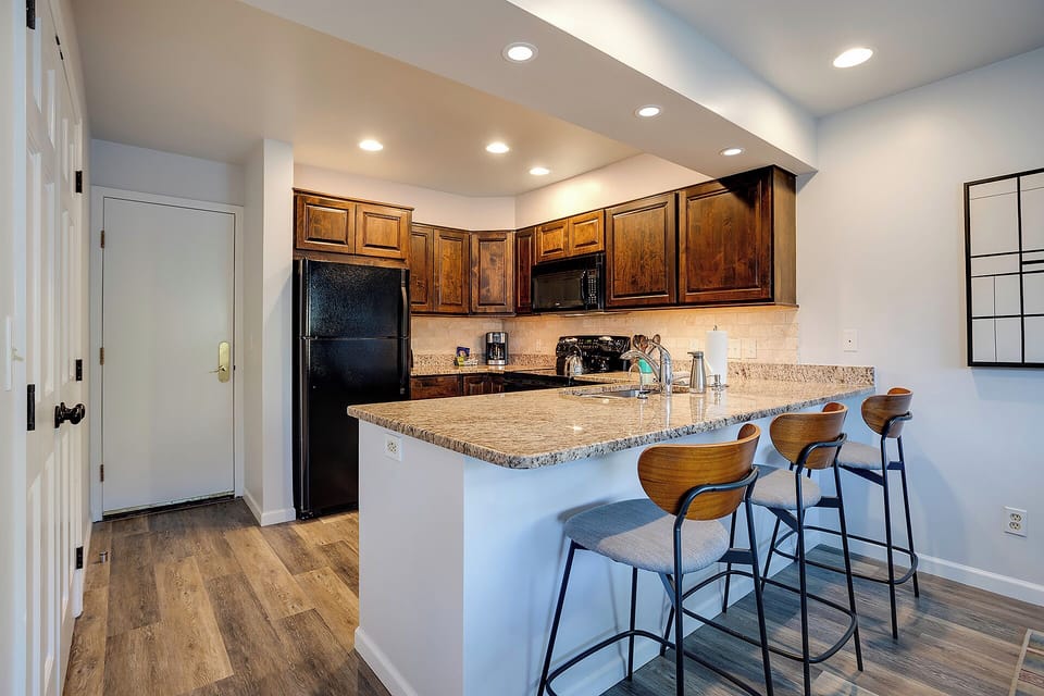 Your fully equipped kitchen features granite counters, warm wood cabinets, and modern appliances—perfect for preparing meals and casual dining at the breakfast bar.