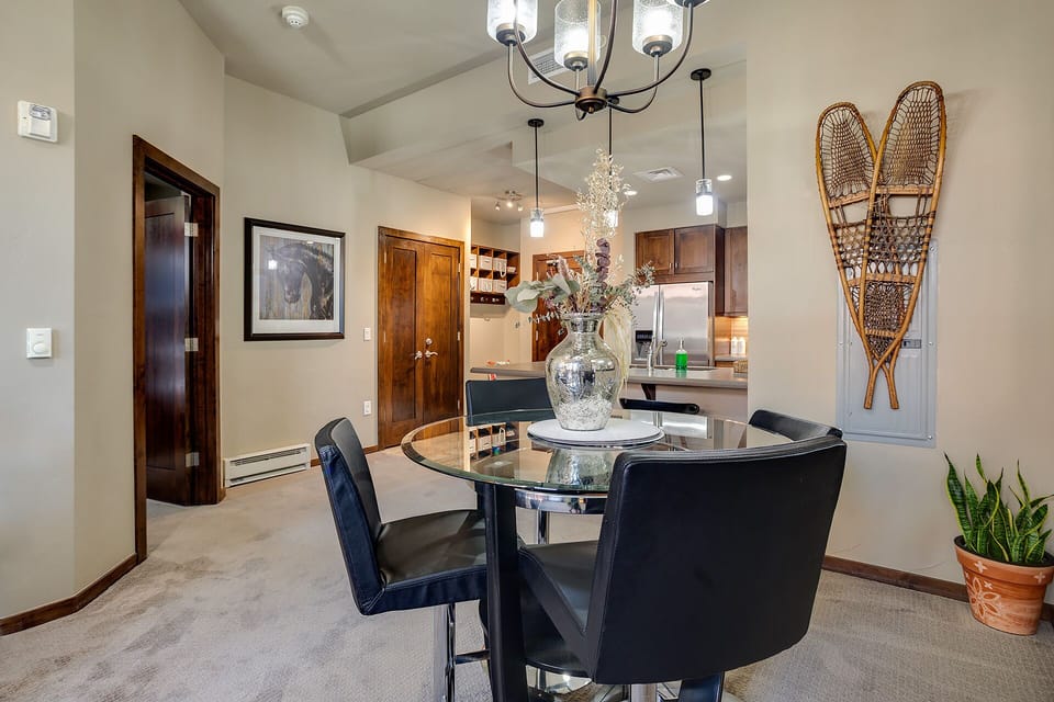 Gather around your elegant glass dining table where warm lighting and rustic touches create the perfect atmosphere for memorable meals together.