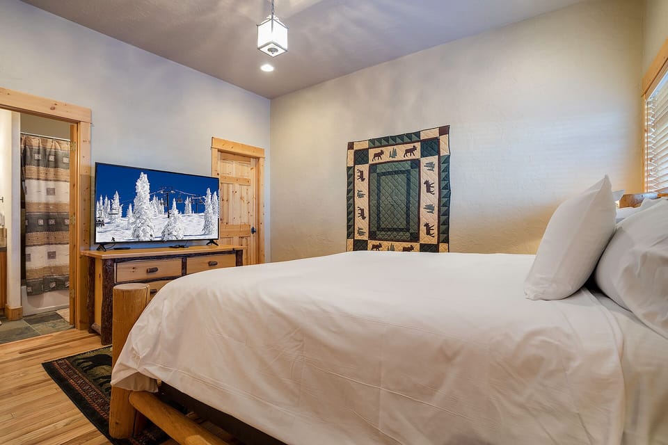 Unwind in your cozy bedroom featuring rustic wood accents, crisp linens, and entertainment at your fingertips.
