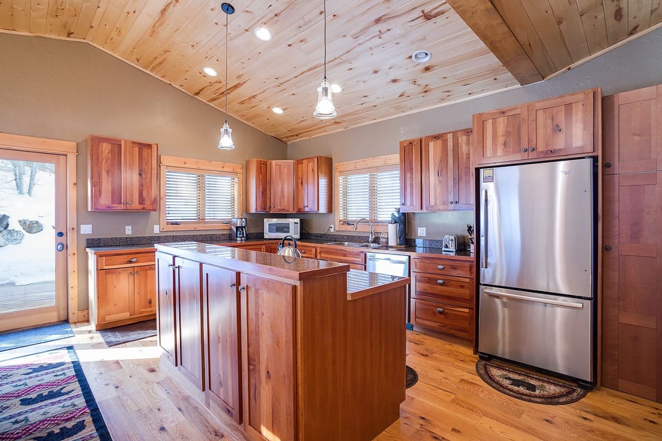 Warm wood cabinetry and rustic charm create your perfect mountain cooking sanctuary with modern stainless appliances and spacious island.