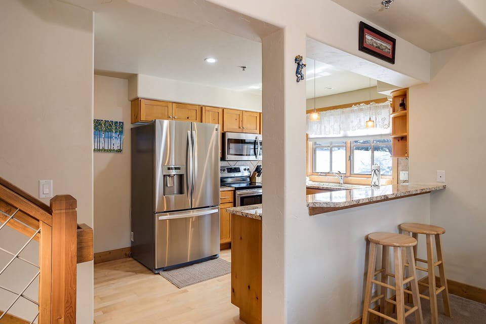 Your spacious kitchen features modern stainless steel appliances and warm wood cabinets, with a breakfast bar perfect for morning coffee.