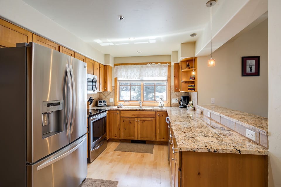 Your fully equipped kitchen features granite countertops, stainless steel appliances, and warm wood cabinetry—perfect for preparing meals.