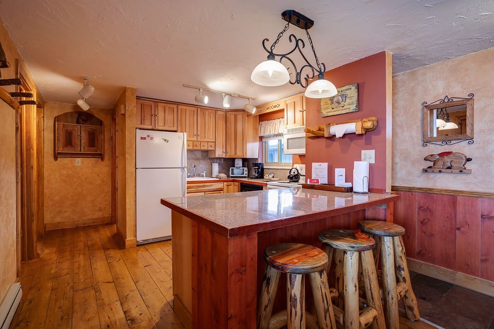 Gather around the rustic wood island with friends and enjoy your morning coffee in this charming cabin-style kitchen, complete with full appliances and warm, inviting finishes.