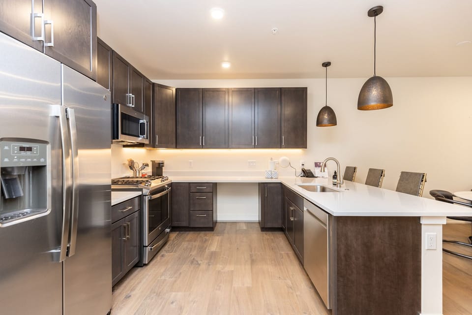 Your sleek kitchen features rich dark cabinetry, gleaming countertops, and premium stainless appliances perfect for creating memorable meals during your stay.