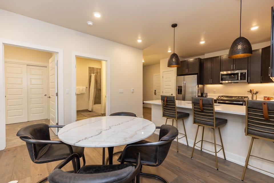 Gather around this marble dining table or at the breakfast bar in your modern kitchen with sleek black cabinetry and pendant lighting.
