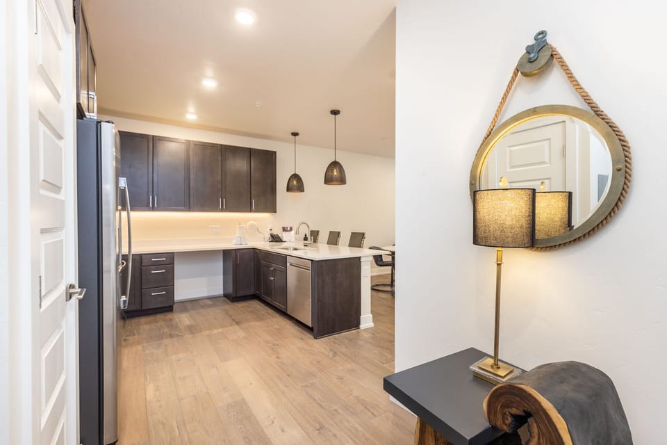 Step into your modern kitchen with sleek dark cabinets, quartz countertops, and stainless steel appliances—perfect for preparing meals together.