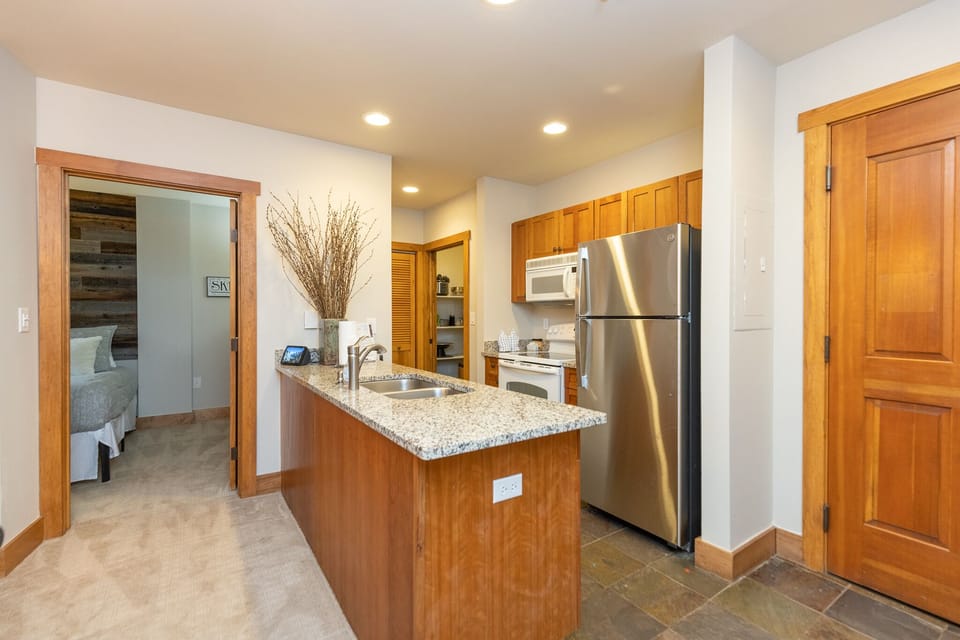 Your spacious kitchen features granite countertops, stainless steel appliances, and warm wood cabinetry - perfect for preparing meals during your stay.