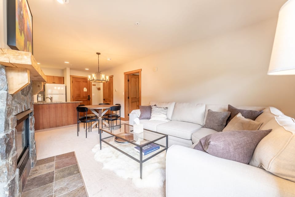 Relax in your spacious living room with plush sectional seating, modern fireplace, and open kitchen perfect for entertaining.