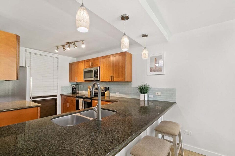 Modern kitchen with granite island, pendant lighting, and bar stools—perfect for morning coffee or casual bites.
