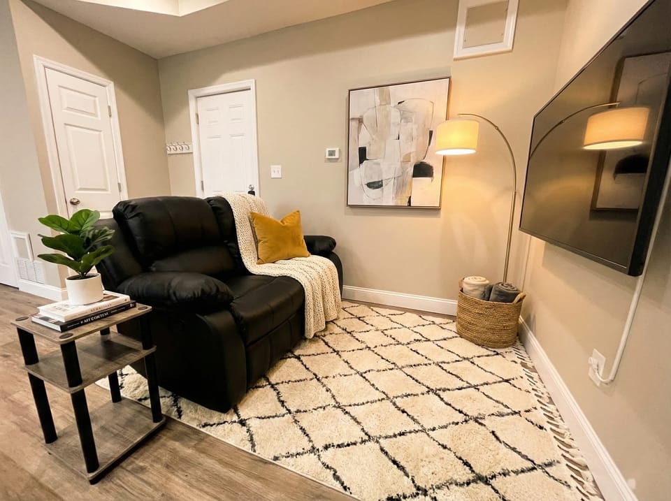 Sitting area with recliner, wall-mounted TV, floor lamp, and area rug.