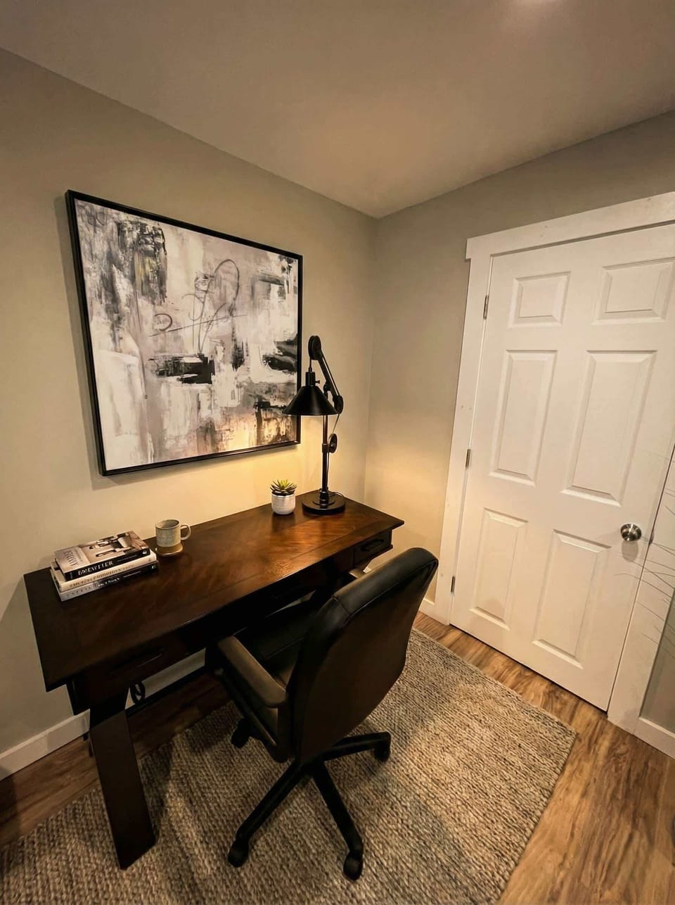 Dedicated workspace with desk, chair, lamp, and wall art.
